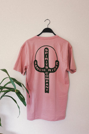 Pink t-shirt with a black design of a cactus and sun. In the cactus, there are pink words that say “Ranch Rider Spirits Company.”