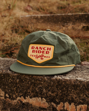 Dark green baseball cap with a yellow detail on the bill and a yellow, white and red patch that says "Ranch Rider Spirits, Tex Mex."